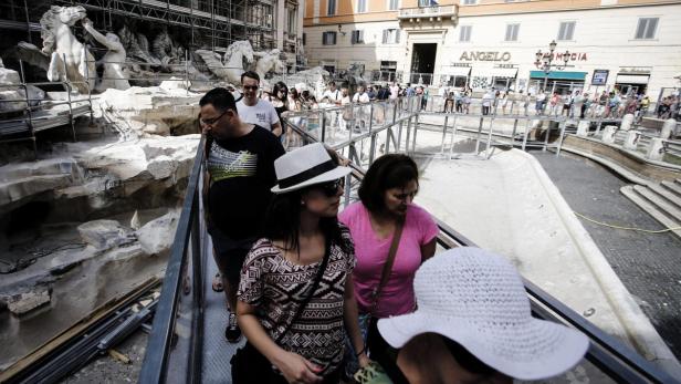 Besucher überqueren die trockene Fontana di Trevi in Rom auf einem Steg.
