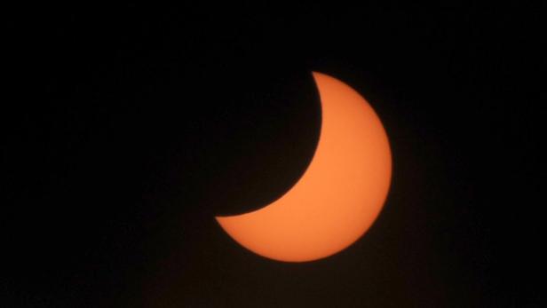 Eine partielle Sonnenfinsternis vor einem dunklen Himmel.
