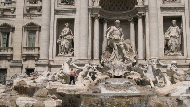 Der Trevi-Brunnen in Rom mit einem Mann, der auf den Felsen steht.