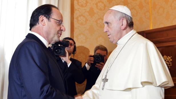 Papst Franziskus schüttelt François Hollande die Hand.