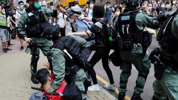 FILE PHOTO: Anti-government demonstrators scuffle with riot police during a lunch time protest as a second reading of a controversial national anthem law takes place in Hong Kong