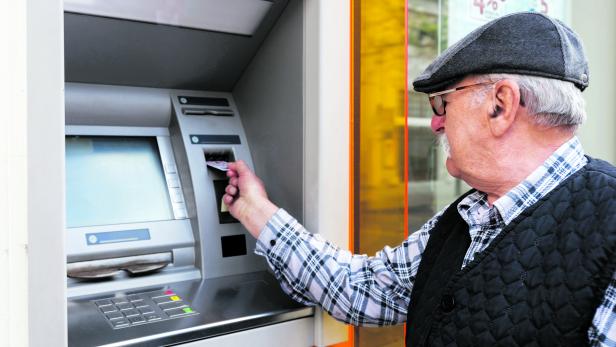 elderly man inserting credit card to ATM