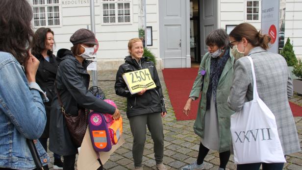 Symbolische Übergabe von Unterschriften aus einer Schultasche an eine Mitarbeiterin der Parlamentsdirektion