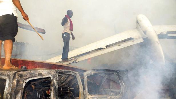 epa03248121 Nigerians stand on the wreckage at the scene of a plane crash in Lagos, Nigeria, 03 June 2012. A domestic passenger plane crashed into a populated area of Lagos, Nigeria&#039;s largest city, killing at least 150 people, authorities reported. The Dana Airlines plane, identified as a Boeing MD83, was badly damaged in the crash and seemed to have burst into flames as it hit the ground. Broadcaster Channels TV said at least 147 passengers were on the flight, including children. There were also casualties on the ground. The crash was being considered one of the worst in the country&#039;s history. EPA/STR