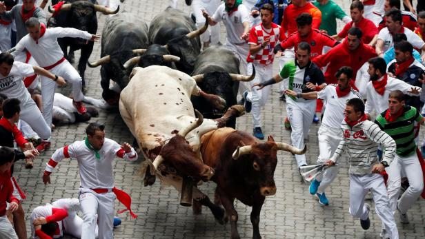 Beim Stiertreiben in Pamplona rennen Menschen vor einer Gruppe Stiere davon.