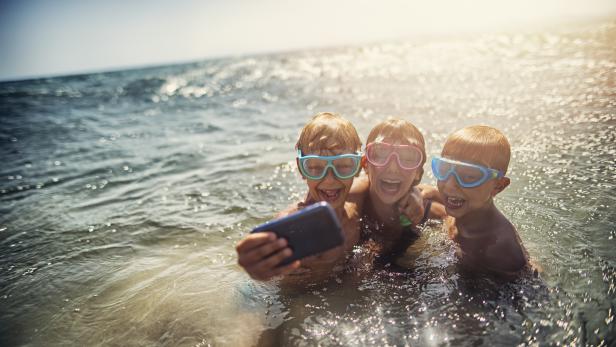 Family taking selfie on a beach in the evening