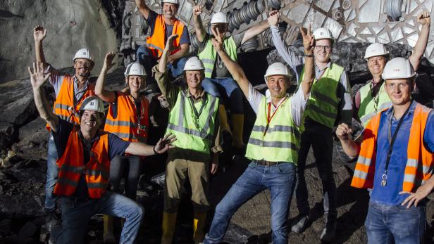 Eine Gruppe Bauarbeiter posiert vor einer Tunnelbohrmaschine.