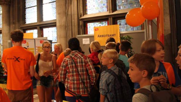 Eine Gruppe von Menschen steht vor einem Stand des Arbeitsamtes.