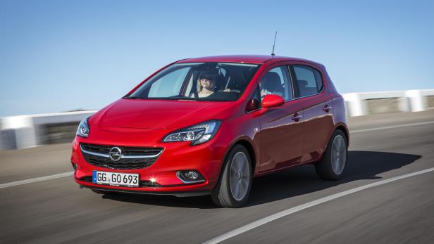 Ein roter Opel Corsa fährt auf einer Landstraße.