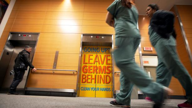 FILE PHOTO: Staff and visitors walk past a sign indicating to wash hands on the elevator doors at the Jewish General Hospital in Montreal