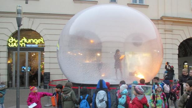 Eine Gruppe Kinder steht vor einer riesigen Schneekugel vor dem Dschungel Wien Theaterhaus.