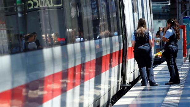 FILE PHOTO: Deutsche Bahn employees stand next to an ICE high-speed train at the main train station in Frankfurt
