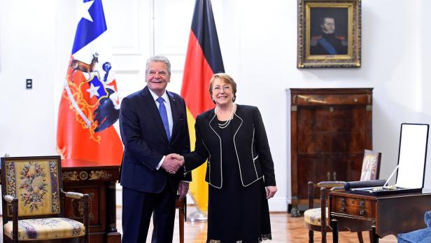 Frank-Walter Steinmeier und Michelle Bachelet schütteln sich die Hände vor chilenischen und deutschen Flaggen.