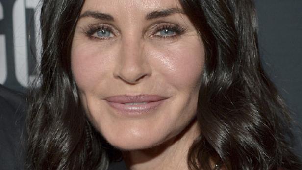 Nahaufnahme von Courteney Cox mit dunklen, gewellten Haaren und blauen Augen.