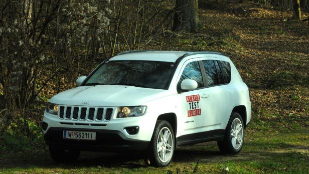 Ein weißer Jeep Compass steht im Gelände.