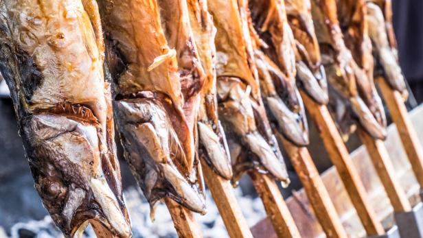 Gegrillter Steckerlfisch auf Holzstäben wird zum Verkauf angeboten.