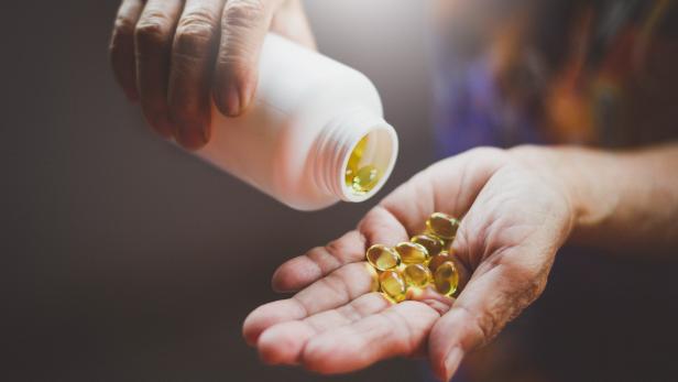Bottle of omega 3 fish oil capsules pouring into hand