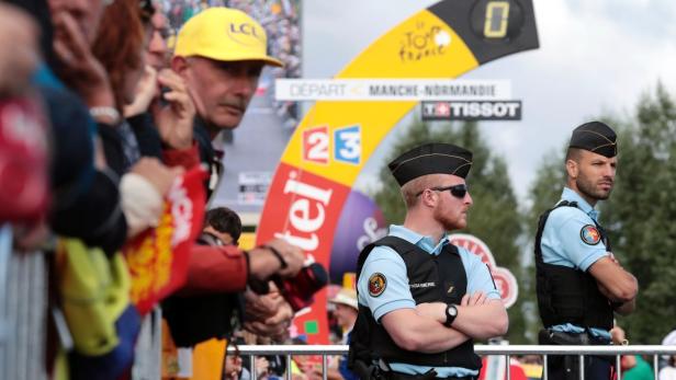 Zwei Gendarmen stehen vor dem Startbogen der Tour de France.