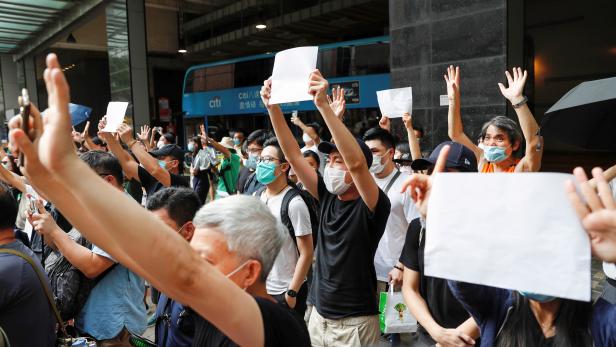 FILE PHOTO: Supporters raise white paper to avoid slogans banned under the national security law as they support arrested anti-law protester outside Eastern court in Hong Kong