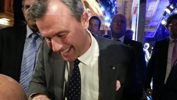 Ein lächelnder Mann im Anzug bei einer Veranstaltung.