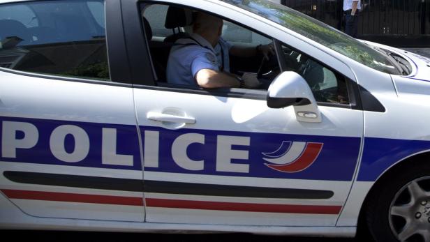 Ein Polizist sitzt in einem französischen Polizeiauto.
