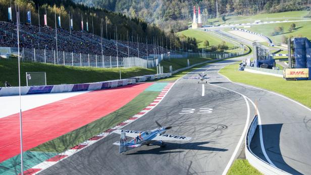 Zwei Flugzeuge auf der Rennstrecke vor einer Zuschauertribüne.