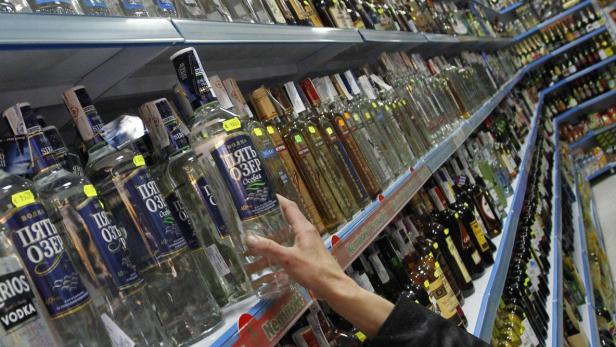 Eine Hand greift nach einer Flasche Wodka der Marke „Пять Озер“ in einem Supermarktregal.