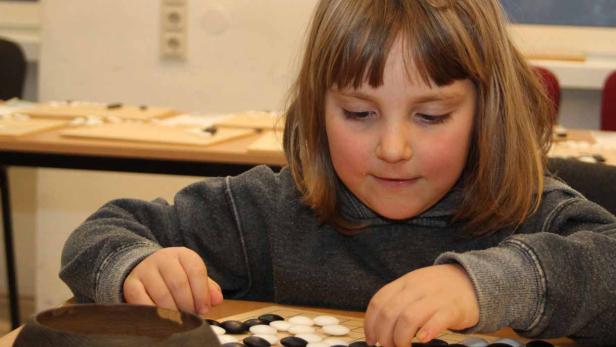 Ein junges Mädchen spielt das Brettspiel Go.