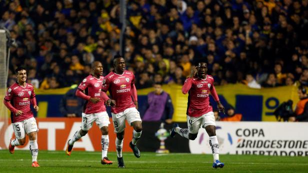 Mehrere Fußballspieler in roten Trikots jubeln auf dem Spielfeld.