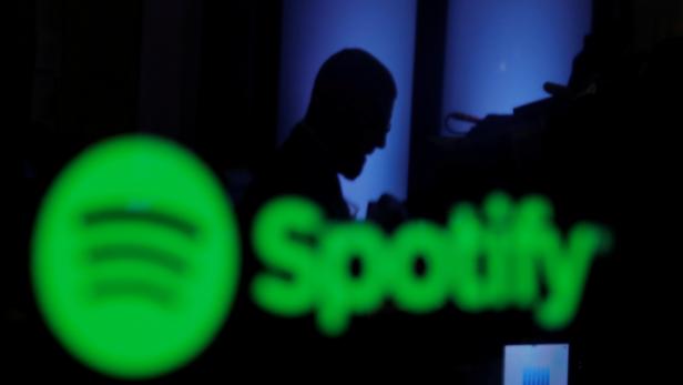FILE PHOTO: A trader is reflected in a computer screen displaying the Spotify brand before the company begins selling as a direct listing on the floor of the New York Stock Exchange in New York