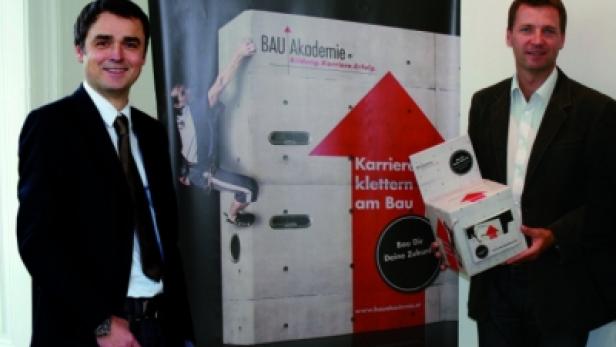 Zwei Männer posieren vor einem Banner der BAU Akademie, das Klettern als Karrieremöglichkeit darstellt.
