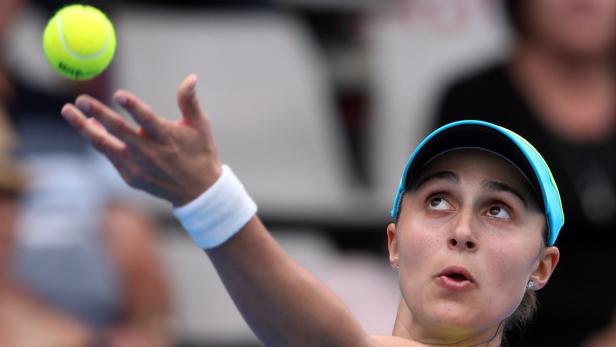 Eine Tennisspielerin wirft einen gelben Tennisball in die Luft, um aufzuschlagen.