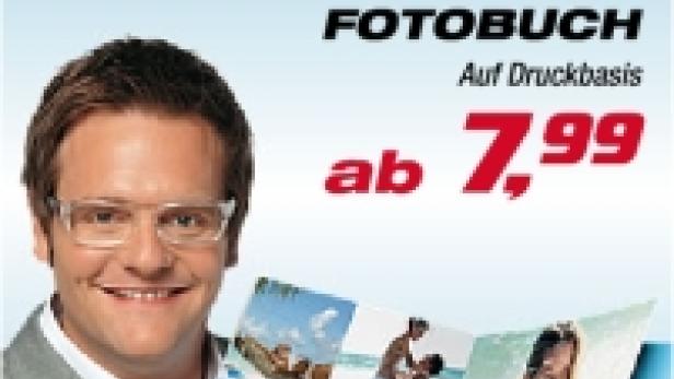 Ein Mann präsentiert ein Hartlauer-Fotobuch mit Sommerfotos; Sonderangebot mit 50% Rabatt.