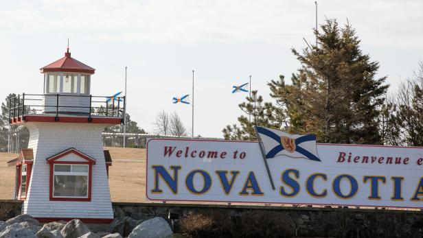 Nova Scotia flags are lowered on the New Brunswick/Nova Scotia border a day after a mass shooting by Gabriel Wortman, in Fort Lawrence