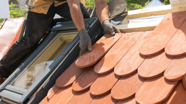 Installing natural red tile. Roof with mansard windows.