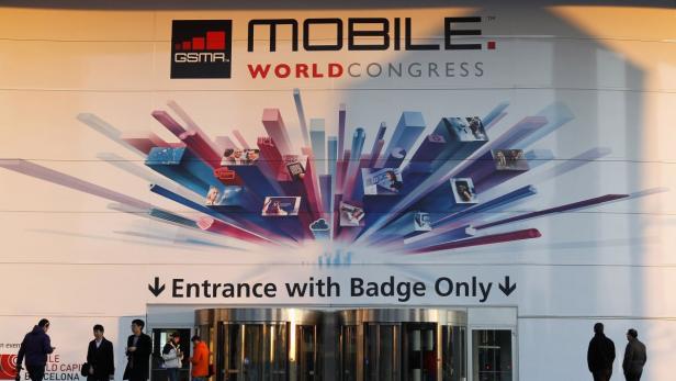 People are seen next to an entrance of the Mobile World Congress, in Barcelona, February 23, 2013. The GSMA Mobile World Congress, representing the interests of the worldwide mobile communications industry, will take place from February 25 to 28 in Barcelona. REUTERS/Albert Gea (SPAIN - Tags: BUSINESS TELECOMS)