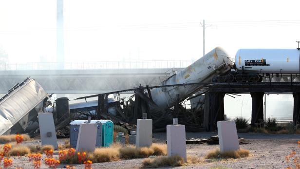 A derailed train burns over a portion of the bridge over Tempe Beach Park in Tempe