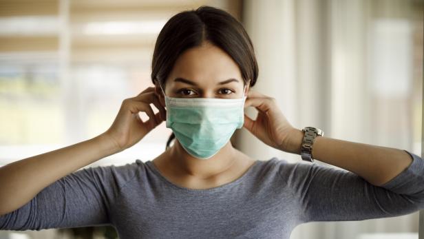 Portrait of young woman putting on a protective mask for coronavirus isolation