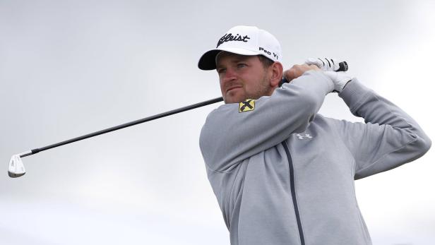 Ein Golfspieler schwingt seinen Schläger vor einem hellen Himmel.