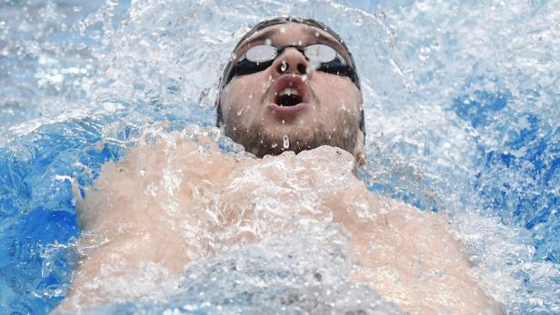 Ein Schwimmer mit Schwimmbrille beim Rückenschwimmen im Wasser.