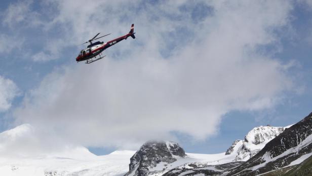 Ein Polizeihubschrauber fliegt über schneebedeckte Berge.