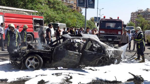 epa03680928 A handout photograph released by Syrian Arab News Agency (SANA) shows firemen working on a burnt out car after a bomb explosion, allegedly targeting Syrian Prime Minister Wael al-Halqi, in Damascus, Syria, 29 April 2013. Syrian Prime Minister Wael al-Halqi survived a bomb attack in Damascus that was apparently targeting his convoy, state television reported 29 April 2013. EPA/SANA / HANDOUT HANDOUT EDITORIAL USE ONLY/NO SALES