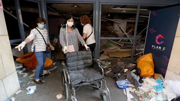 A woman pushes a wheelchair at a damaged hospital following Tuesday's blast in Beirut