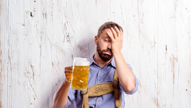 Drunk man in traditional bavarian clothes holding beer mugs
