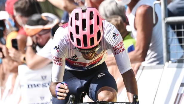 Ein Radrennfahrer mit rosa Helm fährt ein Rennen.