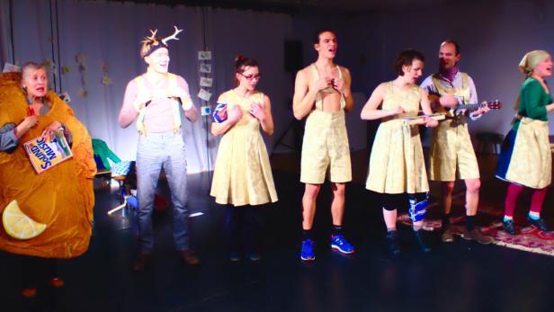 Eine Gruppe von Darstellern steht auf einer Bühne, einige in Kostümen, möglicherweise bei einer Aufführung von „The Sound of Music“.