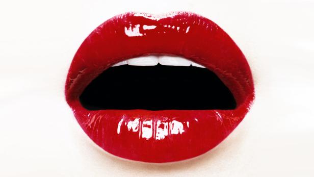 Nahaufnahme eines geöffneten Mundes mit glänzend rotem Lippenstift.