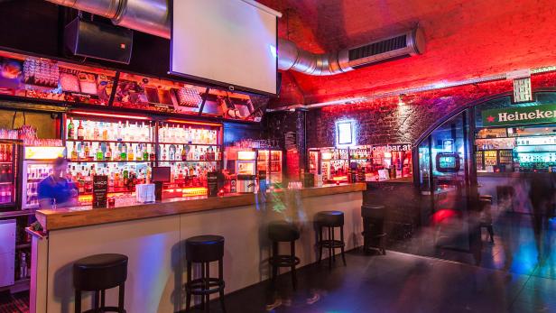 Innenansicht der Bar „Loco“ mit Barhockern und einer großen Auswahl an Spirituosen.