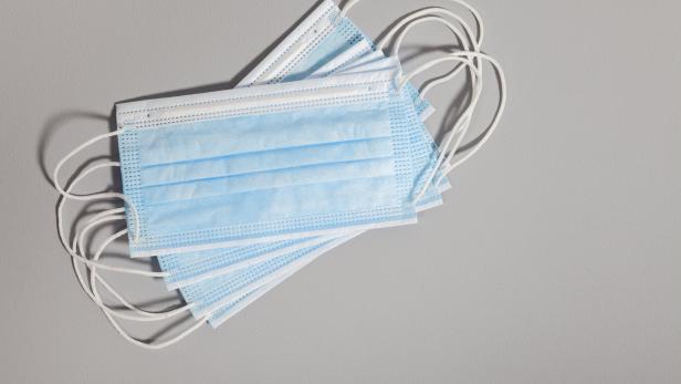 A close-up of a blue surgical mask on a gray background, a hardware mask to protect human health against SARS-CoV-2 or COVID-19 coronavirus infection
