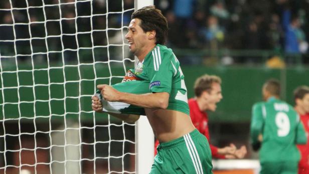Ein Fußballspieler in Grün jubelt und zieht sein Trikot aus.